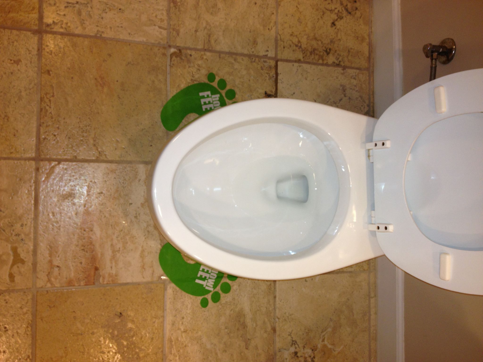 Bowl Feet markers on tan tile floor near toilet